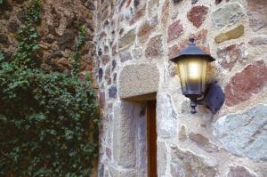 a light on the side of a stone wall at Allotjaments Plaça Major-Boix in Santa Pau