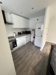 a kitchen with white cabinets and a white refrigerator at Luxury City Centre Apartment in Peterborough