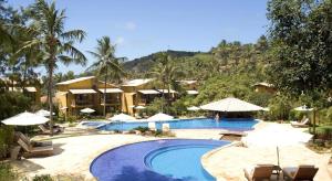 a resort with a swimming pool with chairs and umbrellas at Casa Girassois in Pipa