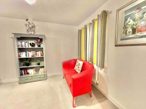 a red chair in a room with a book shelf at Stay in comfort in this large 4 bedroom home in Ashford! in Ashford