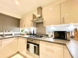 a kitchen with a microwave oven and a stove at Hazel house new 4 bedroom home in Ashford in Ashford