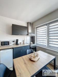 a kitchen with a wooden table with chairs and a tableablish at L'Atelier Zen - Confort & Cosy in Dunkerque