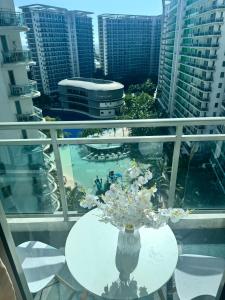 a vase of flowers on a table on a balcony at Manila Azure Staycation By Via & Sabby in Manila