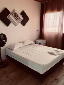 Un dormitorio con una cama con sábanas blancas y una ventana. en Pousada Pé Na Areia 1, en Peruíbe