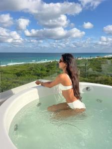 a woman sitting in a bath tub with the ocean at Azulea Isla Mujeres Hotel in Isla Mujeres