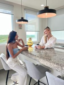 two women sitting at a counter in a kitchen at Azulea Isla Mujeres Hotel in Isla Mujeres