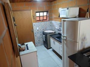 a small kitchen with a refrigerator and a microwave at Chalé Quiririm in Santo Antônio do Pinhal +10 photos