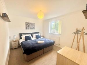 a bedroom with a bed with blue sheets and a window at Lovely modern 4 bedroom House in Ashford in Ashford