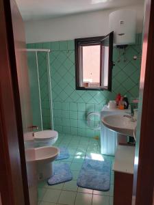 a green bathroom with two sinks and a toilet at Residenza Sa Turritta, Appartamento Marele in Valledoria