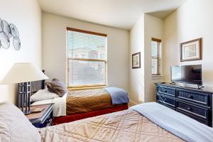 a bedroom with two beds and a flat screen tv at Newpark Townhomes 28 in Park City