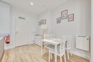 a white dining room with a table and chairs at Premin By Clabao in Pamplona
