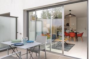 a dining room with sliding glass doors and a table and chairs at Canon proche de la gare maritime au rdc in Vannes