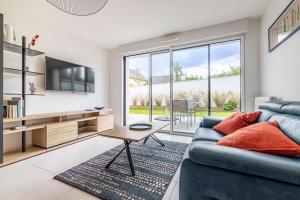 a living room with a blue couch and a tv at Canon proche de la gare maritime au rdc in Vannes
