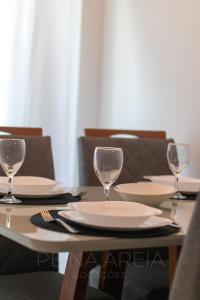 a table with plates and wine glasses on it at Apartamento em Arraial do Cabo- Vista Mar, Piscina e Churrasqueira Privativa na Varanda a 50 m da Praia in Arraial do Cabo +90 photos