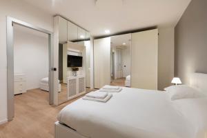 a white bedroom with a large bed and a mirror at Milan Royal Suites Duomo in Milan