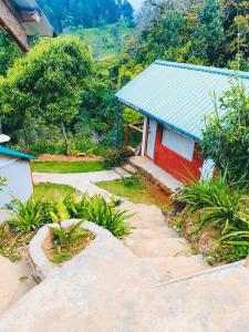a small red house with a blue roof next to a hill at OYA LANGA HENA - Green Park in Hewaheta