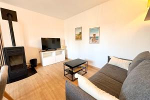 Una sala de estar con un sofá y una chimenea. en Maison entièrement rénovée - À 2 pas des plages, en Ploemeur