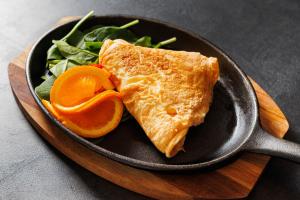 a frying pan with a piece of salmon and a salad at City Premium Heritage in Zadar