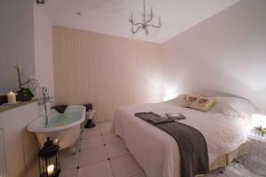 a bedroom with a bed and a sink and a tub at Le Mascaret - Restaurant Hotel Spa - Teritoria in Blainville-sur-Mer
