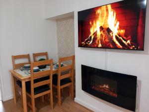 a fireplace in a living room with a table and a fire at Douglas Apartment - Trains to Edin & Glasgow - Private Parking in Airdrie