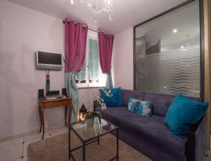 a living room with a purple couch with blue pillows at Le Mascaret - Restaurant Hotel Spa - Teritoria in Blainville-sur-Mer