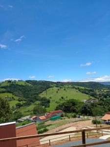 a view of a green hill with houses and trees at Sítio são longuinho in Extrema