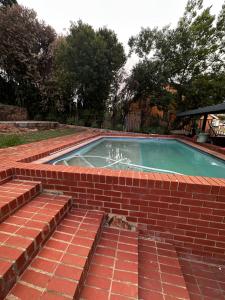 una piscina de ladrillo con una fuente en un patio en Westgate guesthouse, en Roodepoort