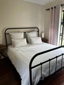 Un dormitorio con una cama con sábanas y almohadas blancas. en Westgate guesthouse, en Roodepoort