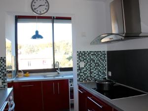 カリー・ル・ルエにあるAppartement bord de merの赤いキャビネット付きのキッチン、窓際の時計