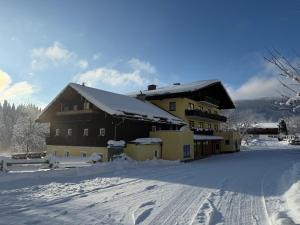 a building covered in snow with a road in front at Hotel Bergglück in Filzmoos