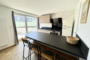 eine Küche mit schwarzer Arbeitsplatte und Kühlschrank in der Unterkunft Joli appartement neuf Jardin 500 m des plages in Larmor-Plage + 10 Fotos