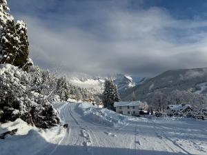 a road covered in snow with trees and a mountain at Hotel Bergglück in Filzmoos