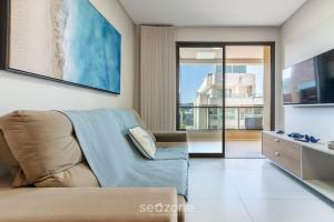 a living room with a couch and a large window at DRL - Apartamentos a 300m da Praia de Bombinhas in Bombinhas