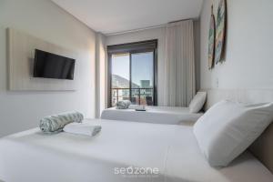 a white room with a bed and a television at DRL - Apartamentos a 300m da Praia de Bombinhas in Bombinhas