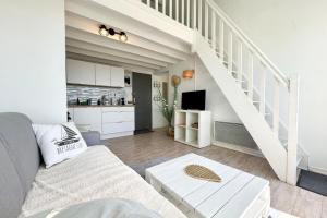 een woonkamer met een bank en een trap bij Superbe appartement duplex - Vue mer - Piscine in Guidel