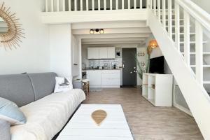 een woonkamer met een bank en een trap bij Superbe appartement duplex - Vue mer - Piscine in Guidel