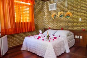 a bedroom with a bed with a white table with flowers on it at Pousada Império do Sol in Pipa