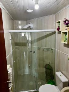 Un baño con ducha de cristal con inodoro. en Apartamento Frente Mar Itapema, en Itapema