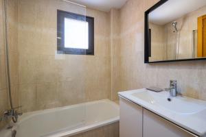 un bagno con un lavandino, una vasca e uno specchio di Atico Gran Esperanza a Fuengirola Altre 11 foto