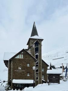 a church with a steeple in the snow at Eurostars La Pleta in Baqueira-Beret
