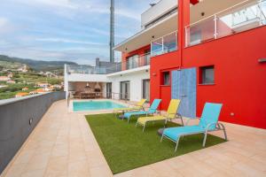 a patio with chairs and a swimming pool on a building at Villa Rodrigues by Amazing Madeira in Ponta do Sol