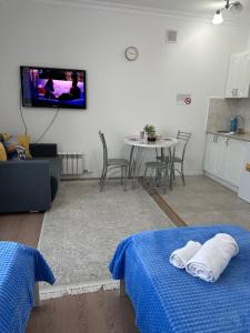 a living room with a table and a tv on the wall at Promenade Burabay in Borovoye