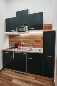 eine kleine Küche mit Spüle und Mikrowelle in der Unterkunft Moon Suite - Taranto Centro - Vasca Idromassaggio in Taranto