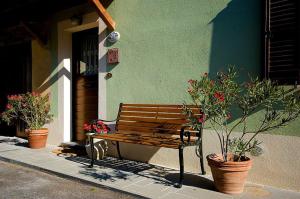 a wooden bench sitting outside of a building with potted plants at Green House - Blue House in Civitella dʼAgliano