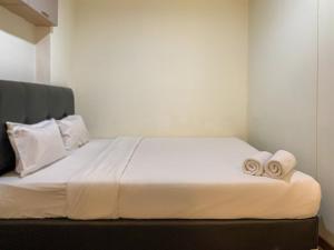 a bedroom with a bed with two towels on it at Warm and Homey 1BR at Belmont Residence Puri Apartment By Travelio in Jakarta