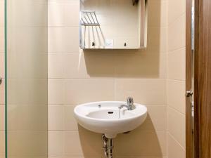 a bathroom with a sink and a mirror at Warm and Homey 1BR at Belmont Residence Puri Apartment By Travelio in Jakarta +17 photos