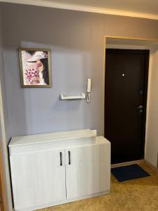 a white cabinet in a room with a black door at Apartments Tsiolkovsky in Pavlodar