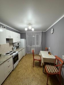 a kitchen with a table and a table and chairs at Apartments Tsiolkovsky in Pavlodar