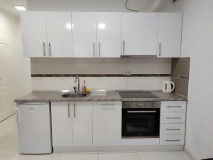 a white kitchen with white cabinets and a sink at Apartments S&S in Konjic