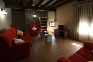 a living room with two red couches and a television at El Rincon Del Villar in Villar de Plasencia